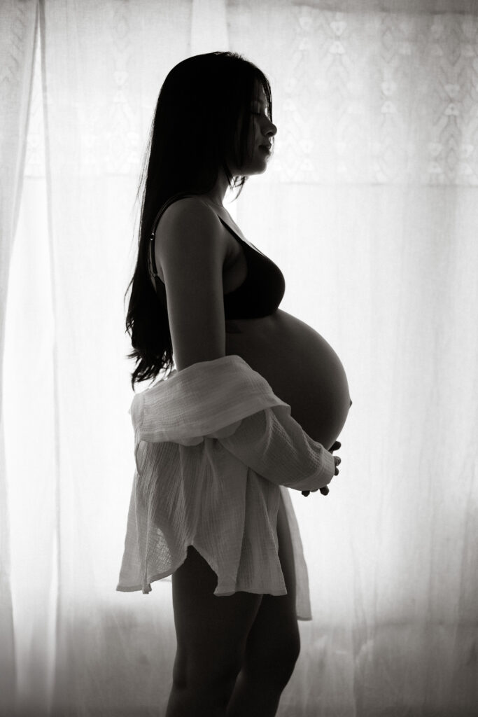 silhouette of pregnant woman standing in front of a window