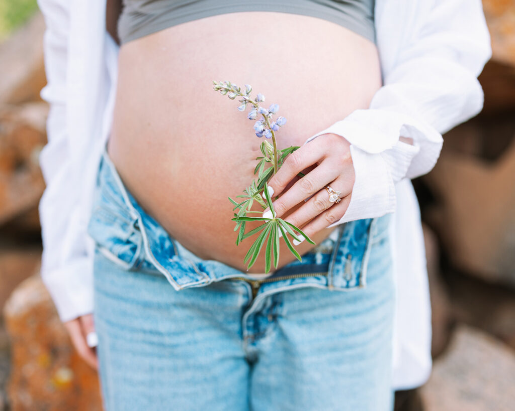 photo of pregnant woman holding a wildflower in front of her belly