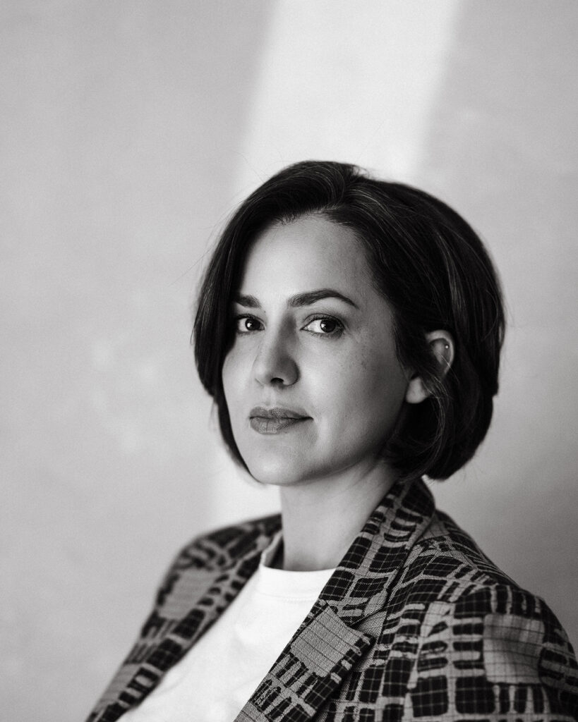 Black and white headshot of a woman in a plaid blazer looking slightly off-camera.
