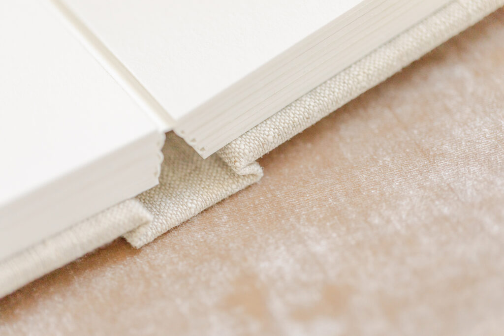 A detailed look at the layflat binding of an heirloom photo album on a blush velvet cover, highlighting the craftsmanship offered by a northern Colorado photographer.
