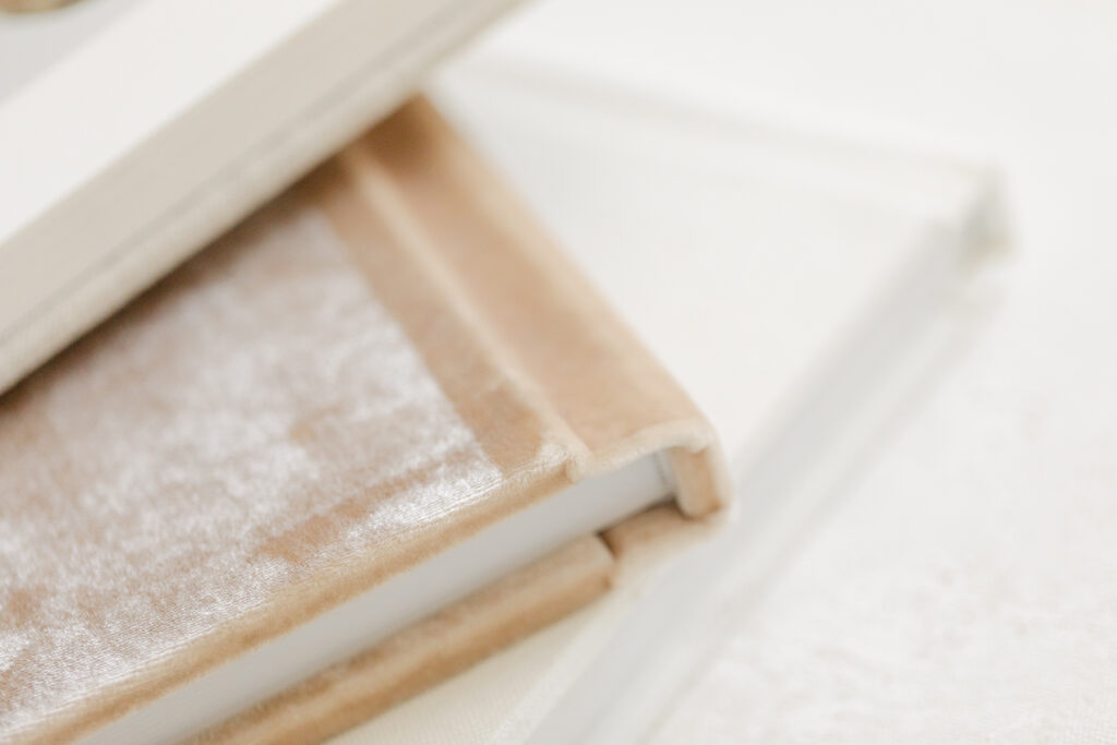 A close-up of a custom velvet photo album stacked over a linen album, showcasing premium materials offered by a Fort Collins photographer for heirloom artwork.