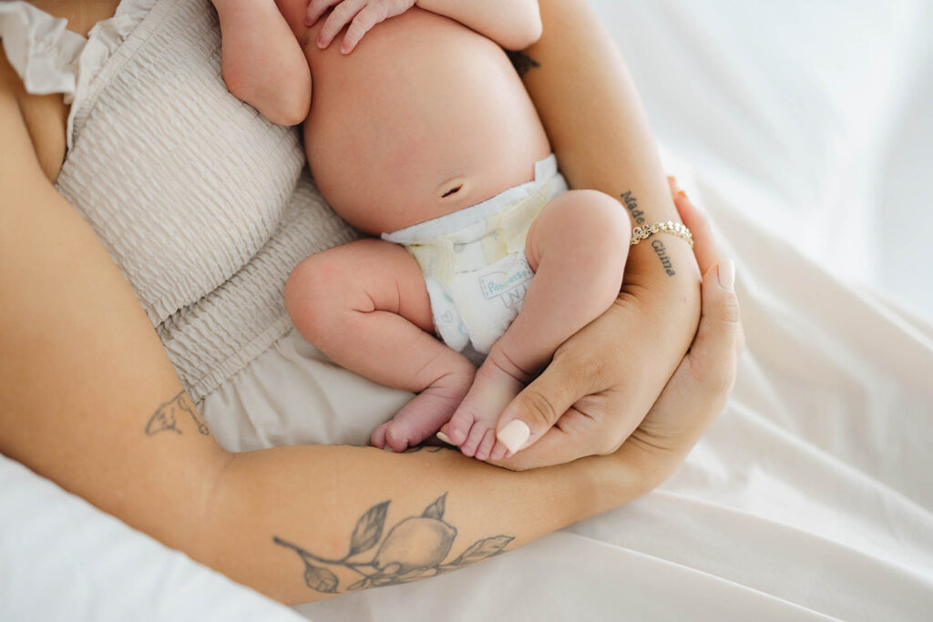 “Newborn baby in a diaper resting in mother’s arms during a natural Fort Collins newborn photography session.”