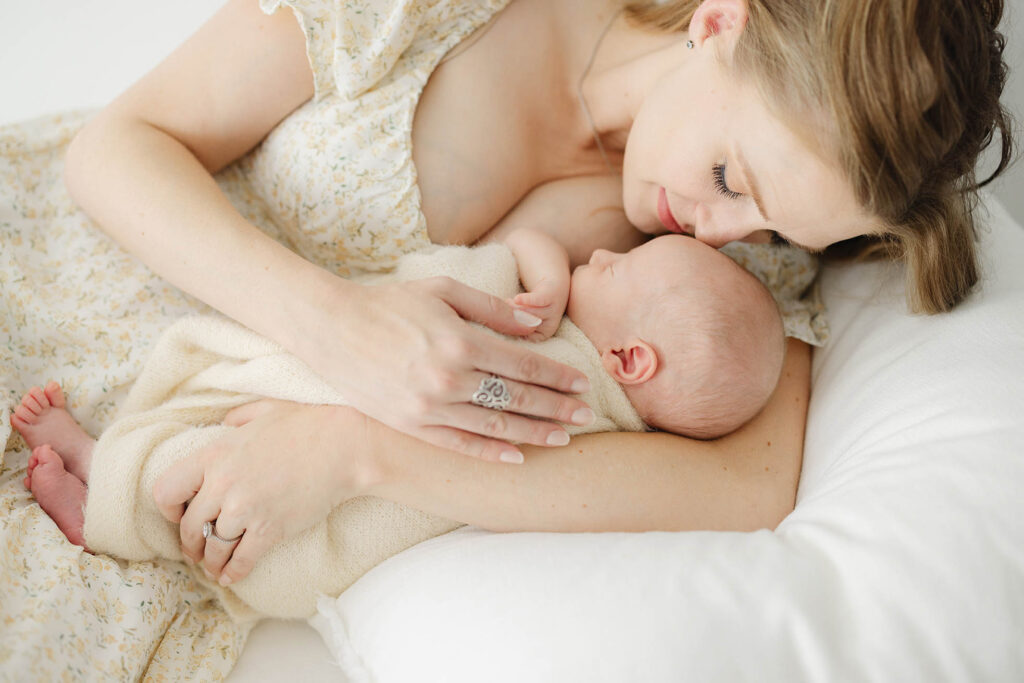 mom laying down and holding newborn baby close