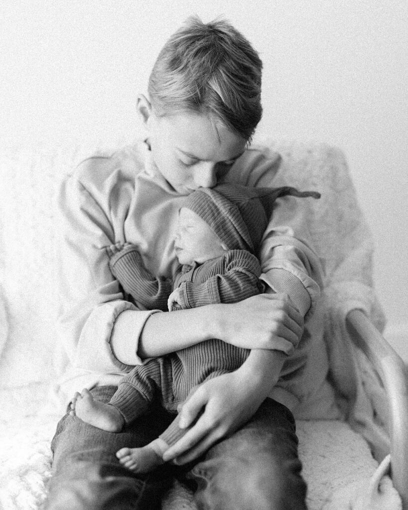 Big brother kissing newborn baby brother