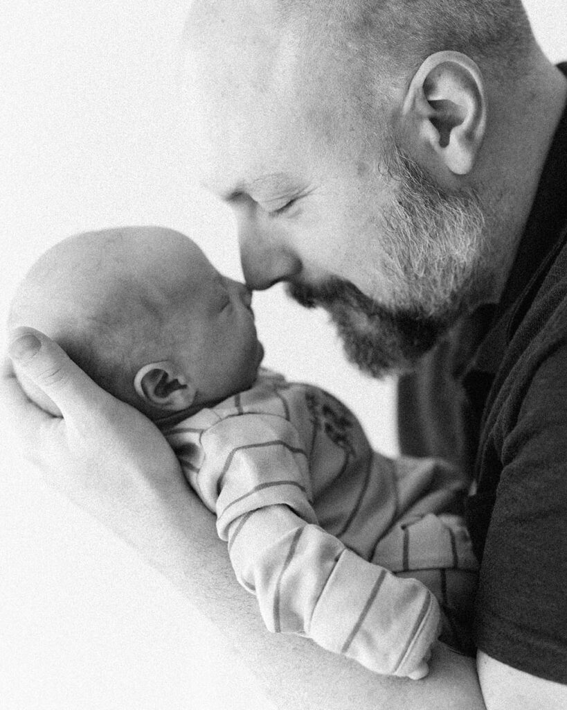dad holding newborn baby close to his face