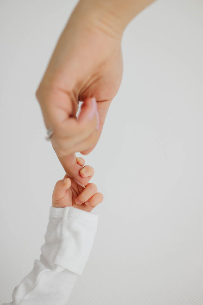 detail shot of newborn baby hand holding onto mom's finger
