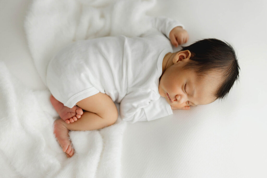 Newborn baby sleeping in all white onesie
