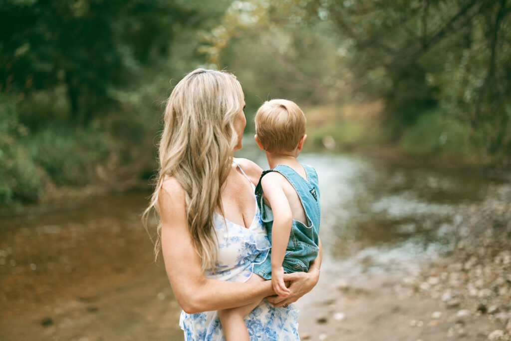 mother holding boy and looking back at stream behind them