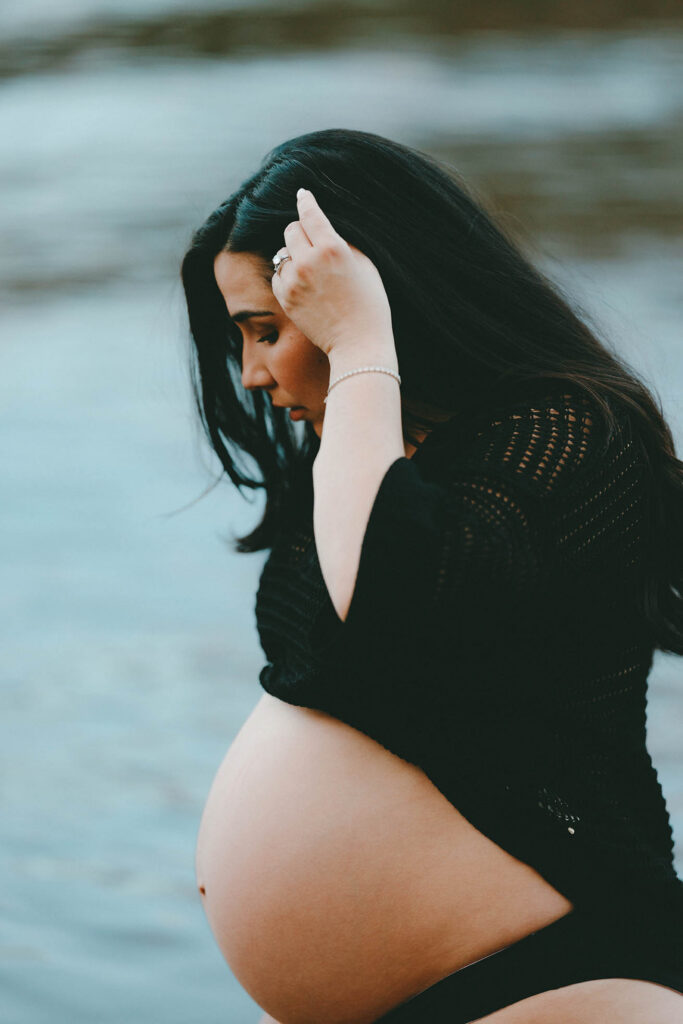 photo of pregnant woman looking down at belly and pulling her hair out of her face