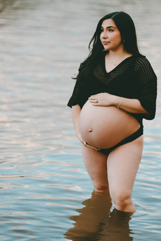 phot of pregnant woman gaving to the side with both hands on her belly