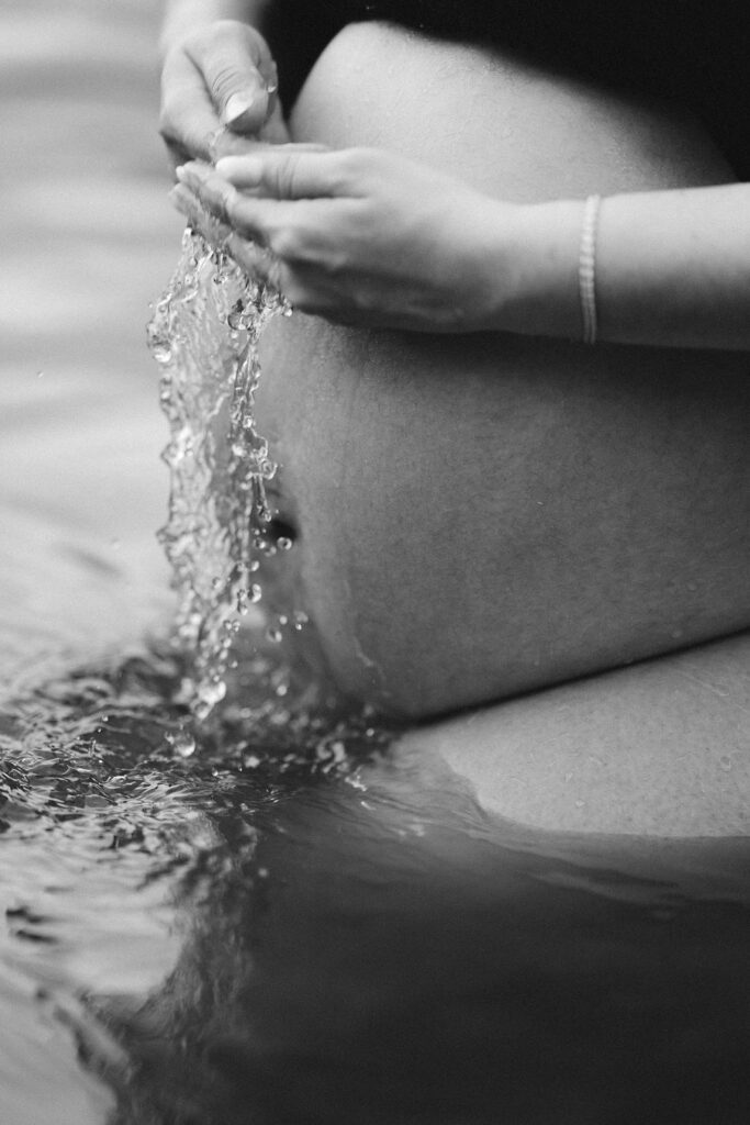 close up photo of pregnant belly and mother's hands pouring water over her own belly