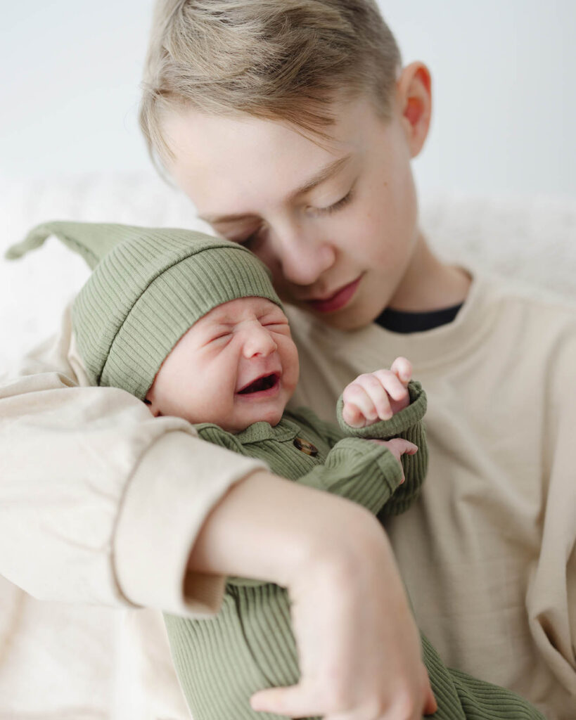 Big brother holding newborn baby brother
