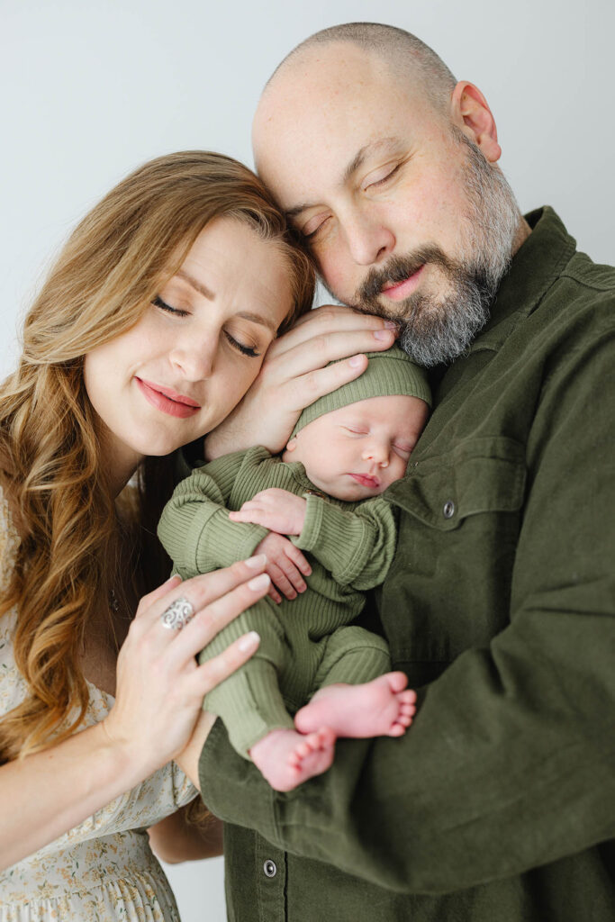 photo of two parents holding newborn baby between them