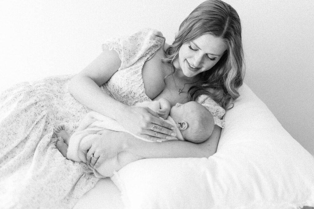 photo of mother laying next to newborn bay and gazing down at him