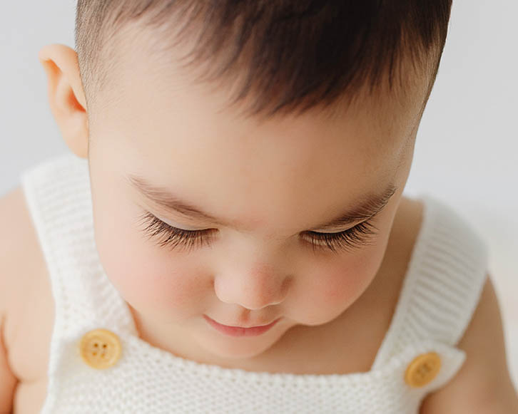 close up of baby looking down showing long eyelashes and soft features during sitter milestone session