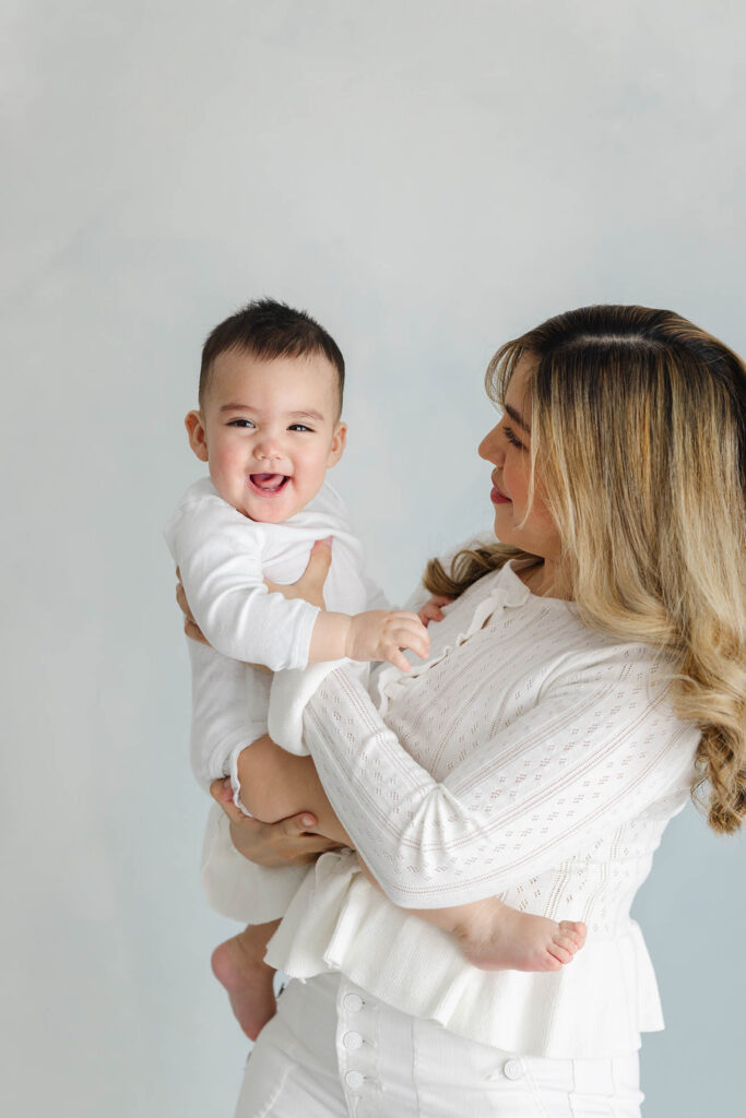 mother holding happy baby and looking at him while he laughs