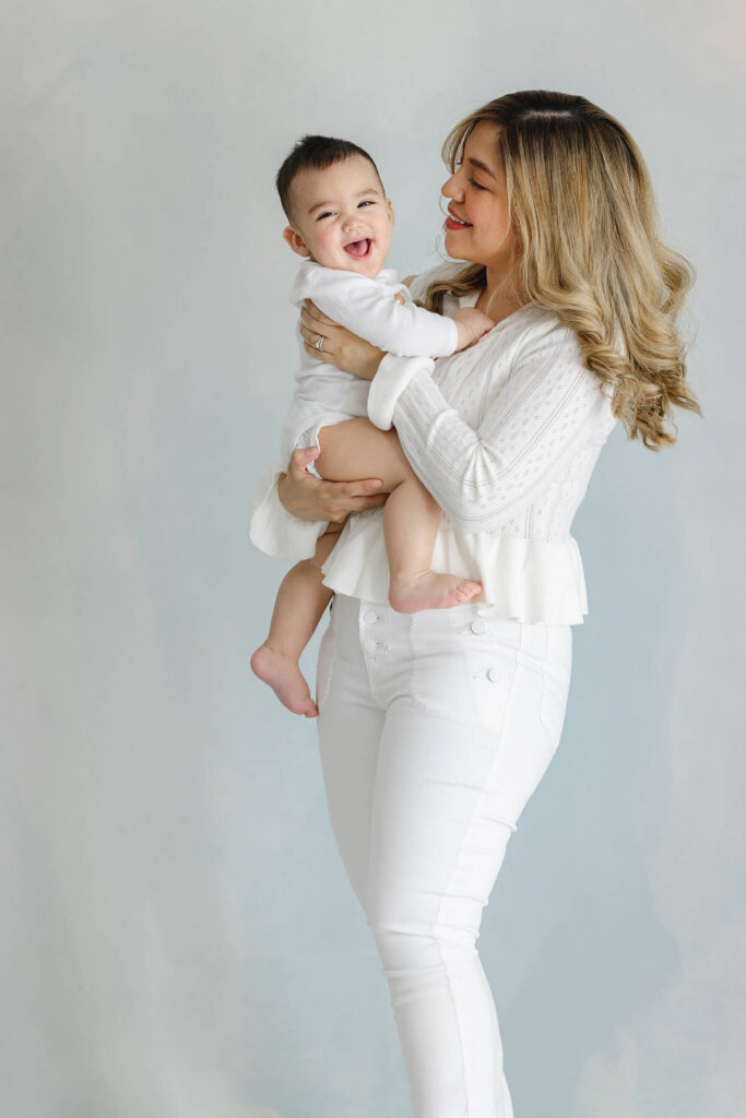 mother holding smiling baby during studio milestone session