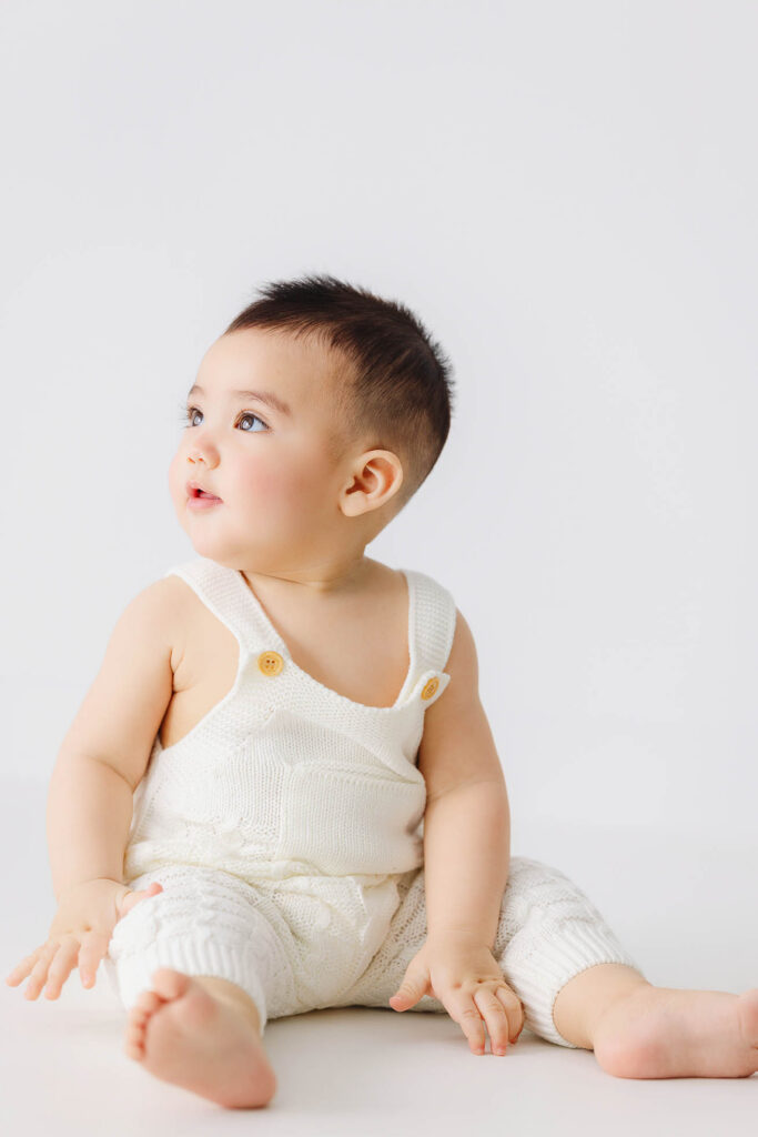 6 month baby sitting sideways in neutral studio setting during sitter milestone session