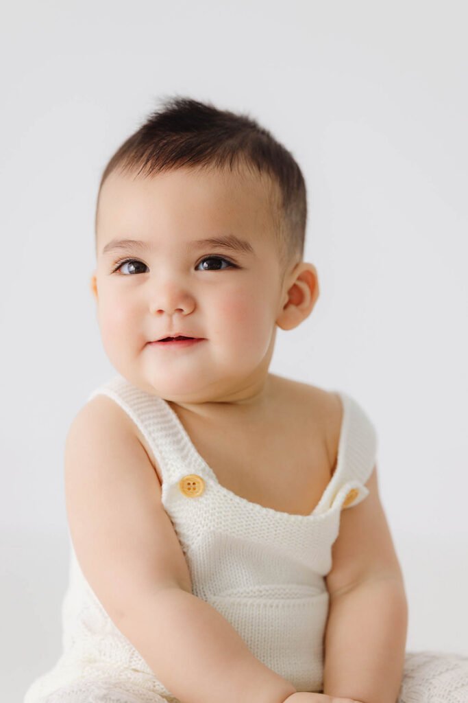 6 month baby sitting in studio looking at camera during milestone photos in Fort Collins