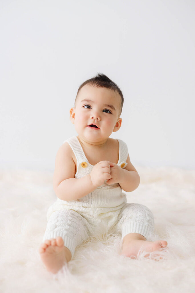 6 month baby sitting independently in studio wearing cream knit outfit during milestone photos in Fort Collins
