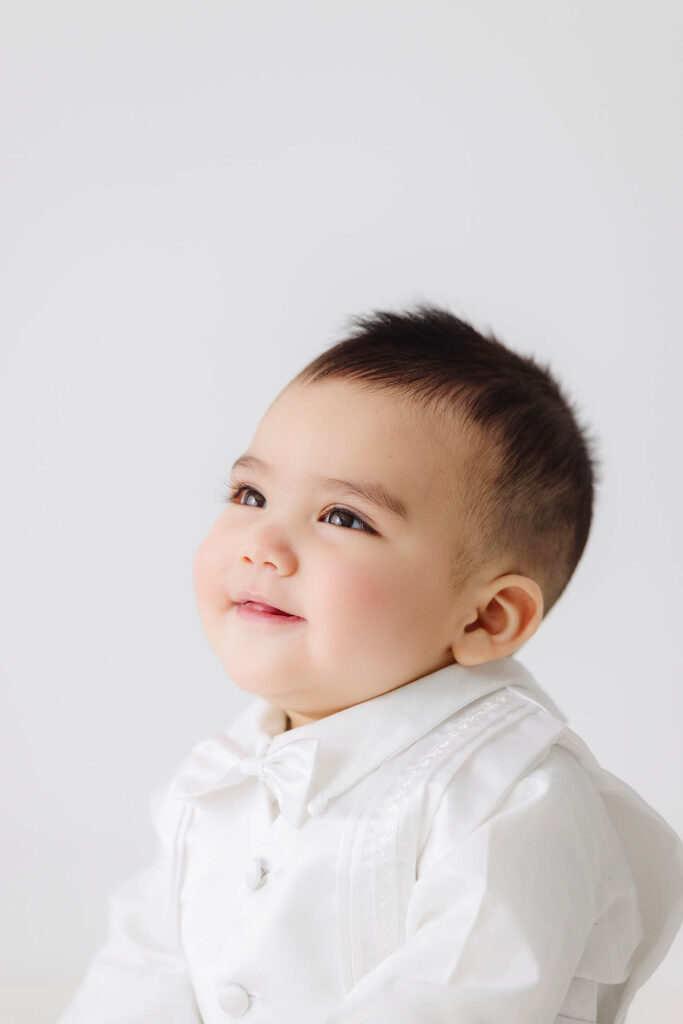 close up of 6 month baby smiling in white outfit during baby milestone session in studio