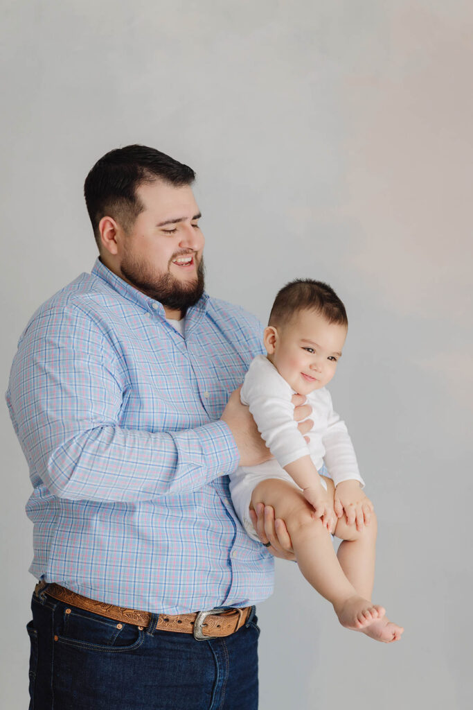 father holding smiling baby during studio milestone session