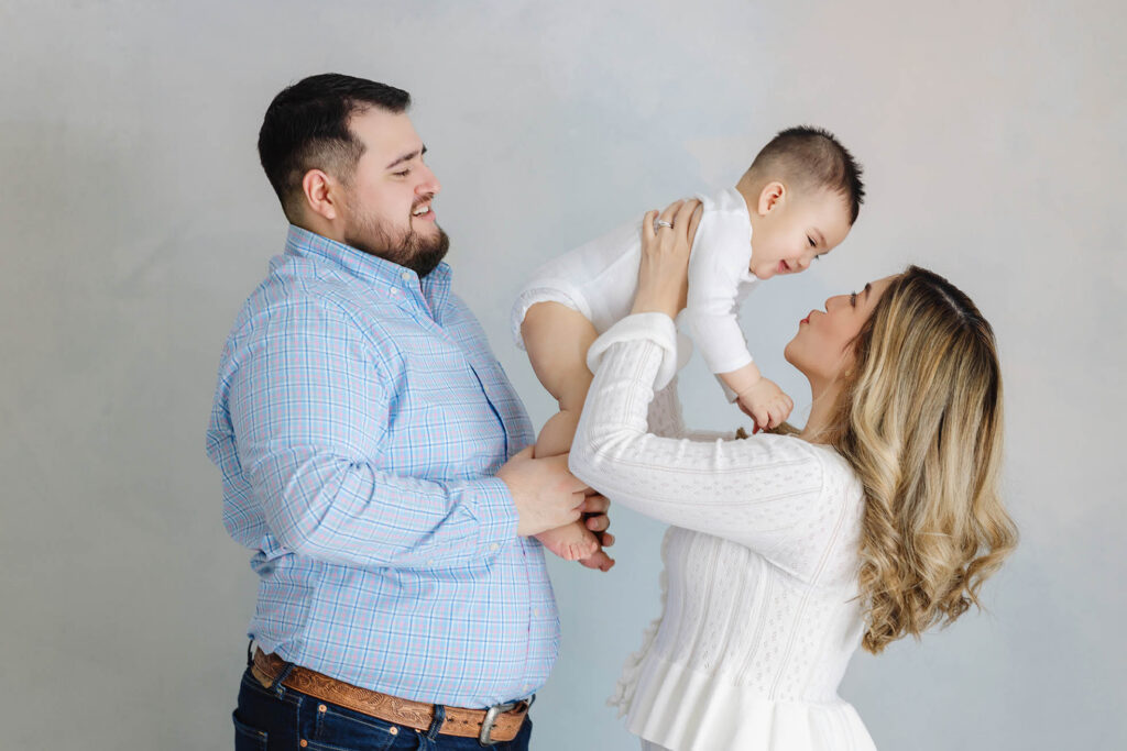 family milestone session with parents lifting baby