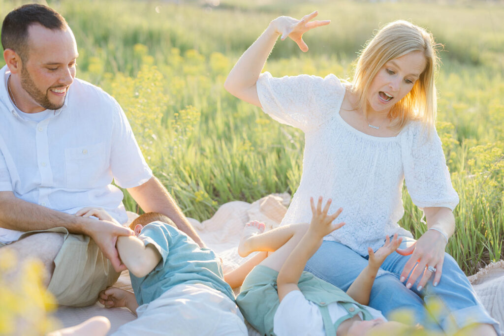 family playing and joking around on a picnic blanket
