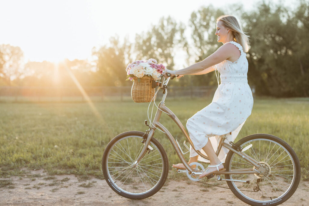 dreamy photo of a woman riding a bike in summer with a dreamy sun flare lighting