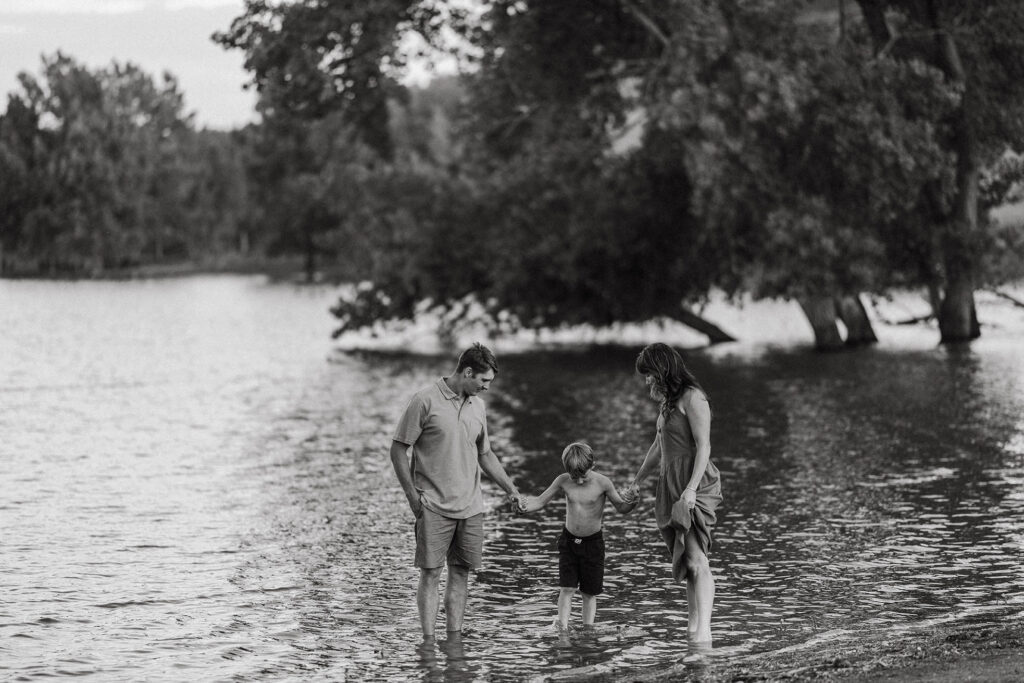 two parents each holding the hand of their son as they play in the water at Horsetooth reservoir