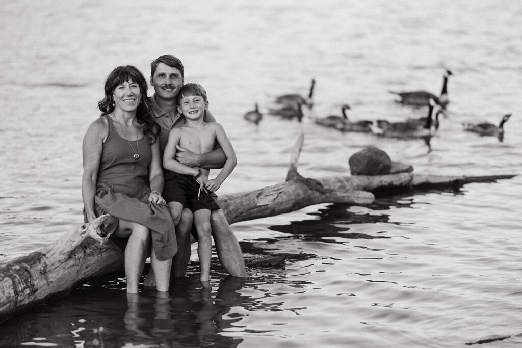 Family sitting on a big log over Horsetooth reservoir water