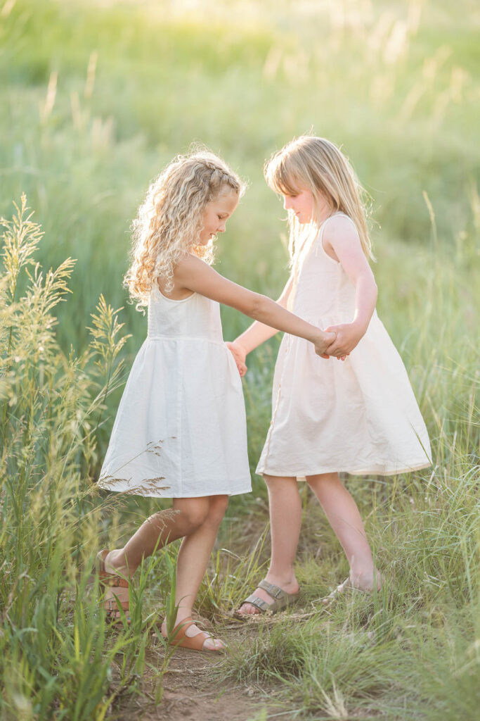 two girls holding all for hands and twirling together