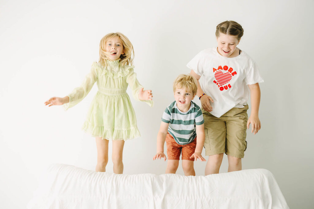 three kids jumping on a couch