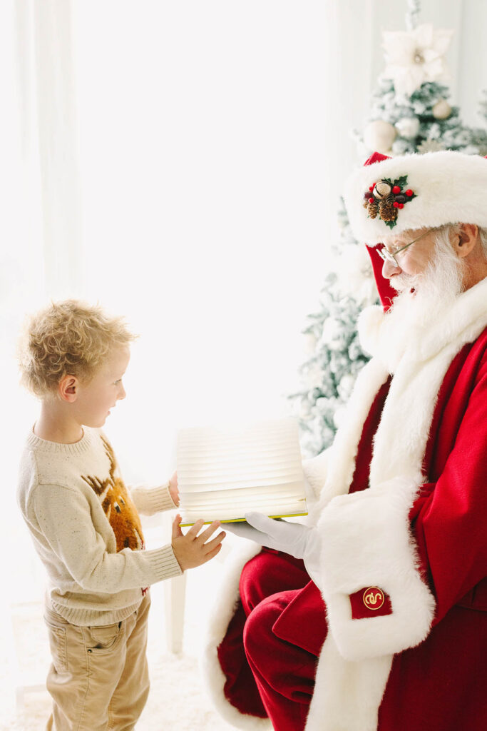 Santa sharing his Nice List book with a boy as the boy looks on with joy to see he's on the Nice List