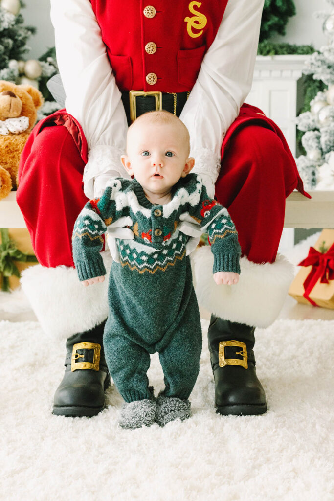 Baby in standing in front of Santa's legs